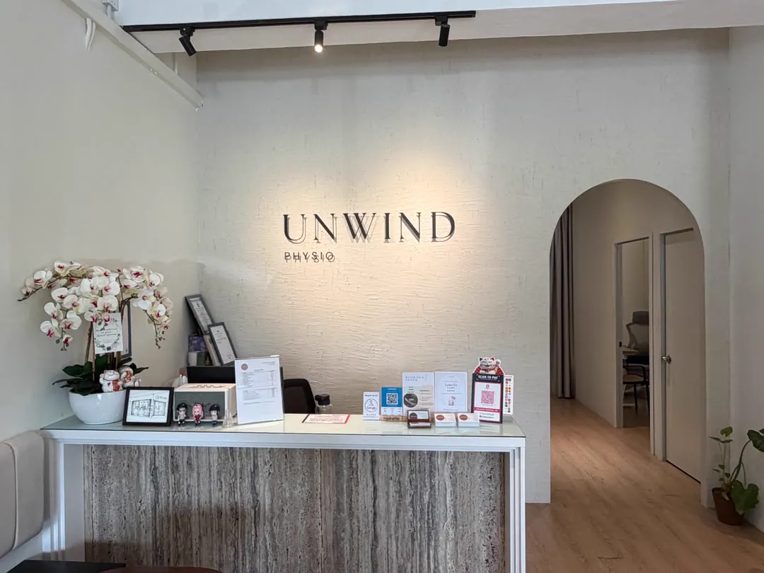 Reception area at Unwind Physio with the brand wall and orchid